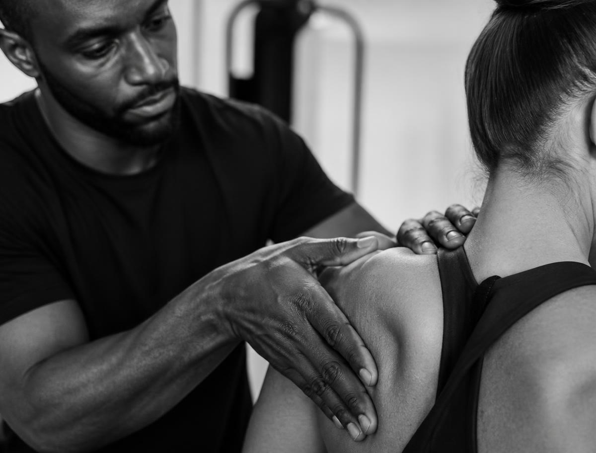 Practitioner's hands assessing an athlete's shoulder